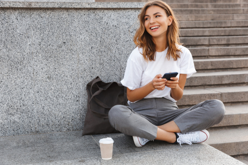 Girl sitting on step playing with phone 