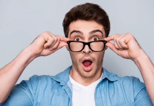 man lifting his glasses in amazement at his perfect vision from lasik