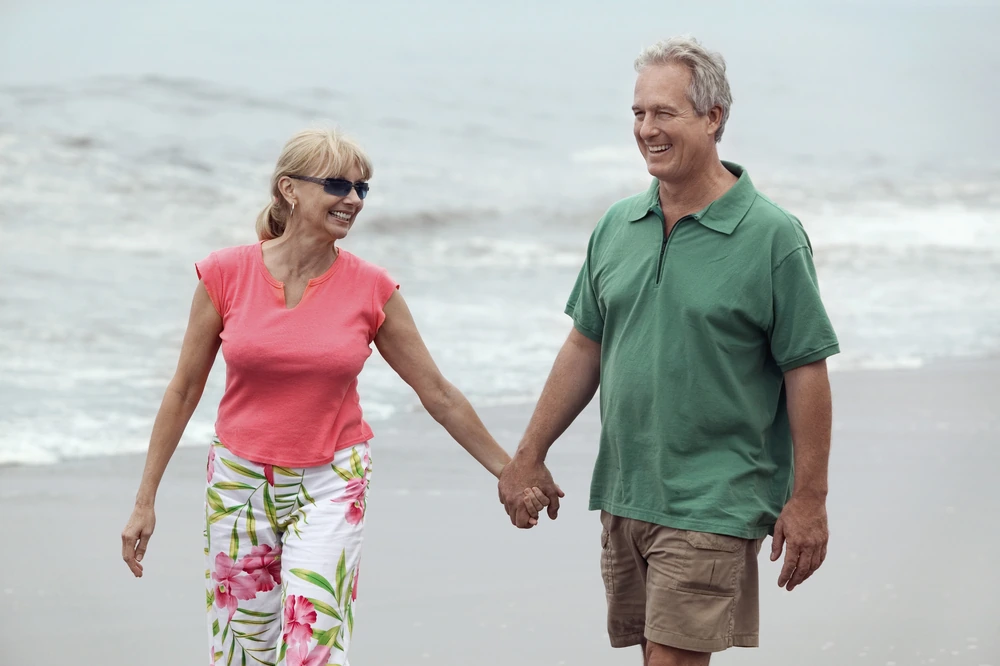 couple in 50s walking on beach